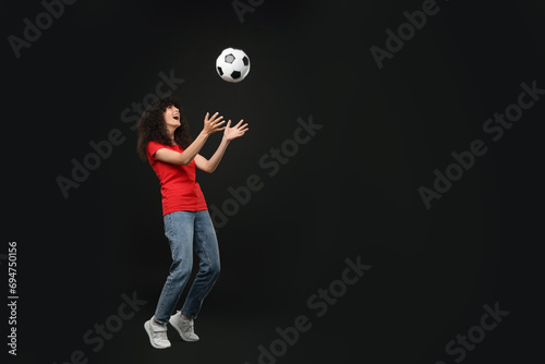 Happy fan playing with soccer ball on black background, space for text