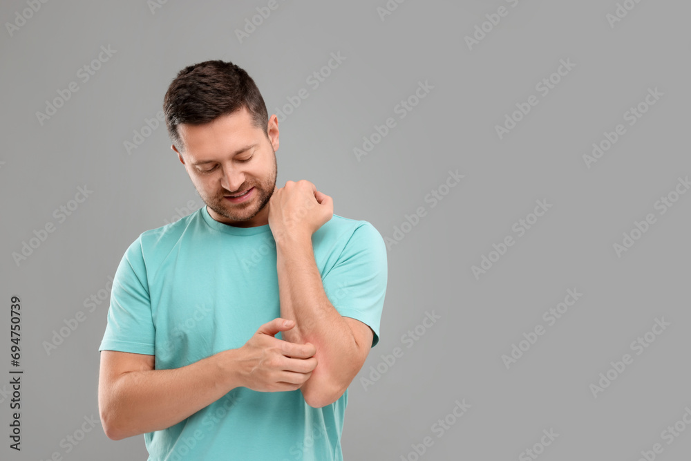 Allergy symptom. Man scratching his arm on light grey background. Space for text Allergy symptom. Man scratching his arm on light grey background. Space for text