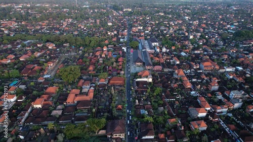 Calming evening view of Ubud town from above, camera fly back and tilt up, reveal distant view of famous city. Main street seen down below, central districts with palace and market at left and right photo