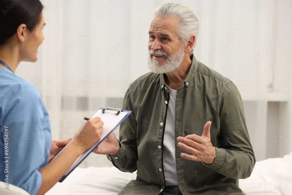 Obraz premium Smiling elderly patient talking with nurse in hospital
