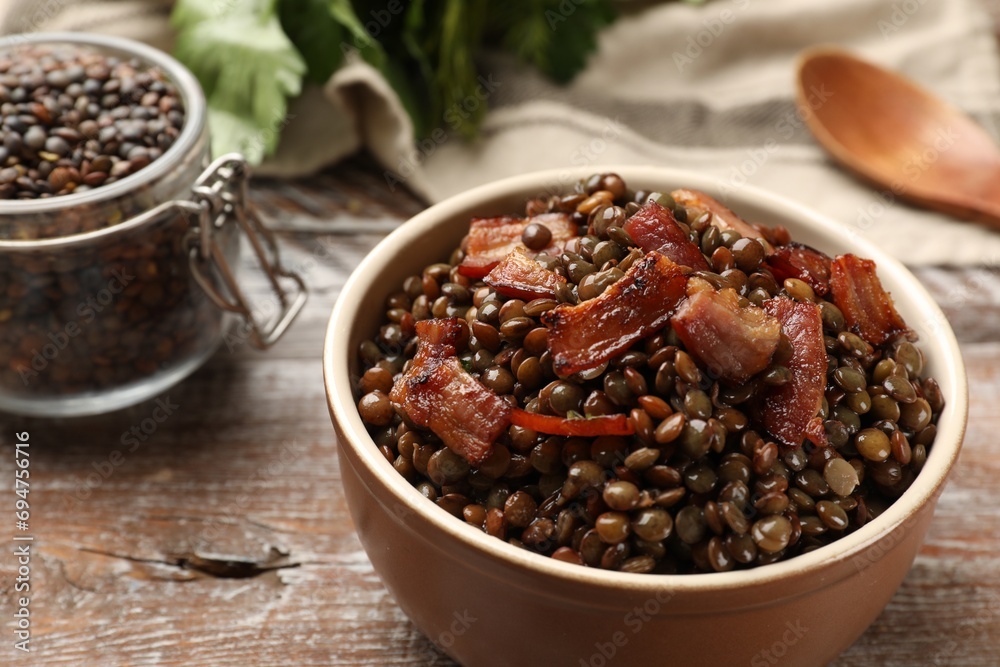 Delicious lentils with bacon in bowl on wooden table, closeup Delicious lentils with bacon in bowl on wooden table, closeup
