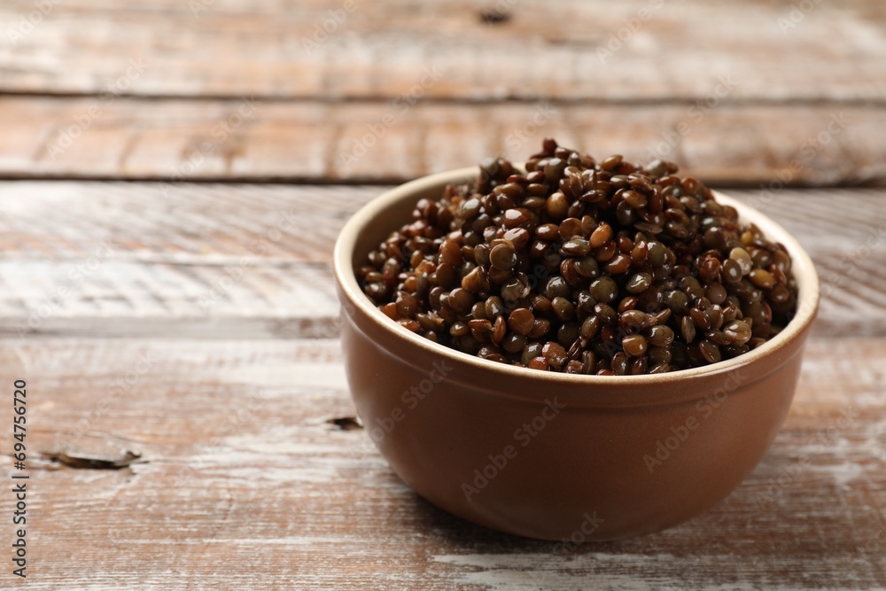Delicious lentils in bowl on wooden table, closeup. Space for text Delicious lentils in bowl on wooden table, closeup. Space for text