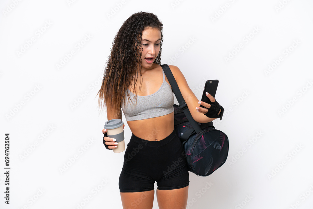 Young sport Arab woman with sport bag isolated on white background holding coffee to take away and a mobile Young sport Arab woman with sport bag isolated on white background holding coffee to take away and a mobile