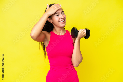 Young sport woman making weightlifting isolated on yellow background smiling a lot