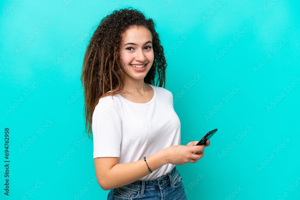 Young Arab woman isolated on blue background sending a message or email with the mobile Young Arab woman isolated on blue background sending a message or email with the mobile