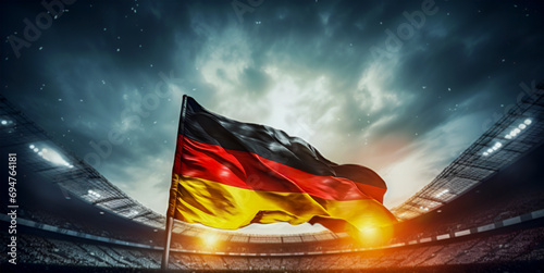 Waving national flag of Germany above blurred football arena in front of dramatic sky. photo