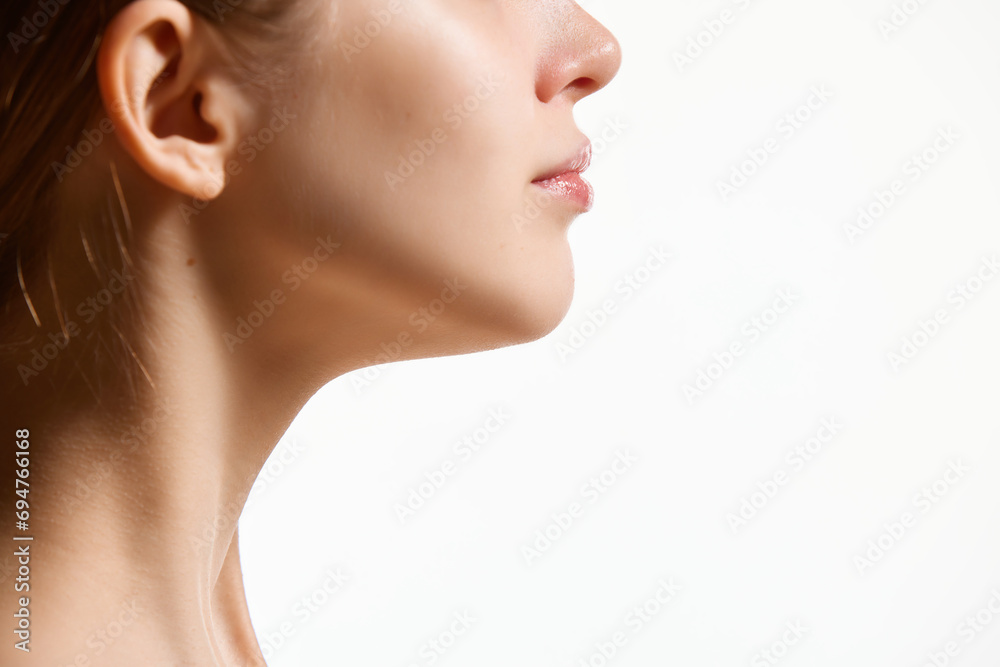 Cropped side view image of female face, neck isolated against white studio background. Reduction of double chin. - obrazy, fototapety, plakaty 