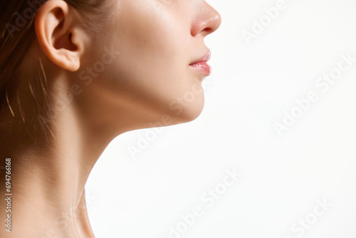 Cropped side view image of female face, neck isolated against white studio background. Reduction of double chin. photo