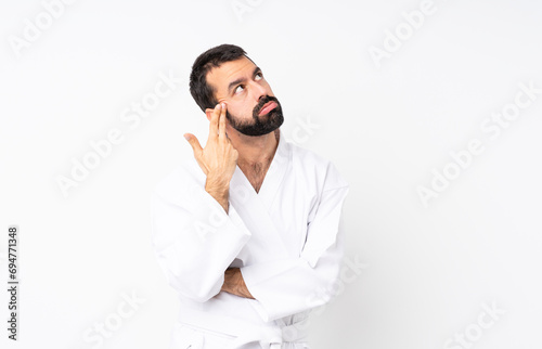 Young man doing karate over isolated white background with problems making suicide gesture