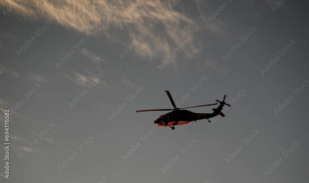 Fototapeta premium Isolated high resolution image of a distant Israeli air- force black hawk helicopter with a beautiful sunset background