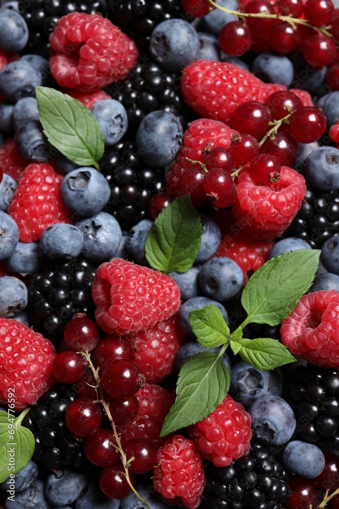 Assortment of fresh ripe berries with green leaves as background, top view Assortment of fresh ripe berries with green leaves as background, top view