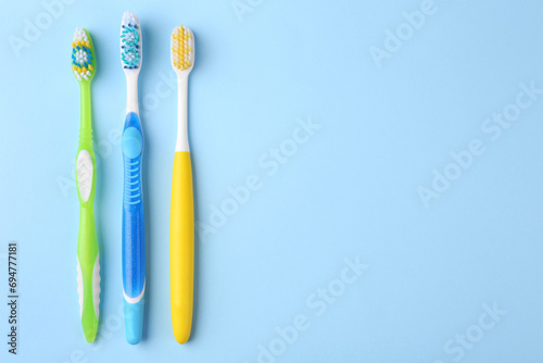 Many different toothbrushes on light blue background  flat lay. Space for text