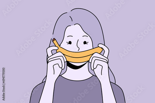 Woman with fake banana smile experiencing frustration and melancholy caused by problem in relationship with boyfriend. Girl holds tropical fruit, wanting to hide frustration associated with losing job