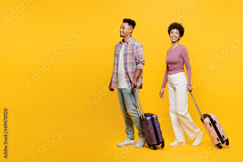 Traveler couple two friend family man woman wearing casual clothes hold suitcase bag go isolated on plain yellow background. Tourist travel abroad in free time rest getaway. Air flight trip concept. #694781126