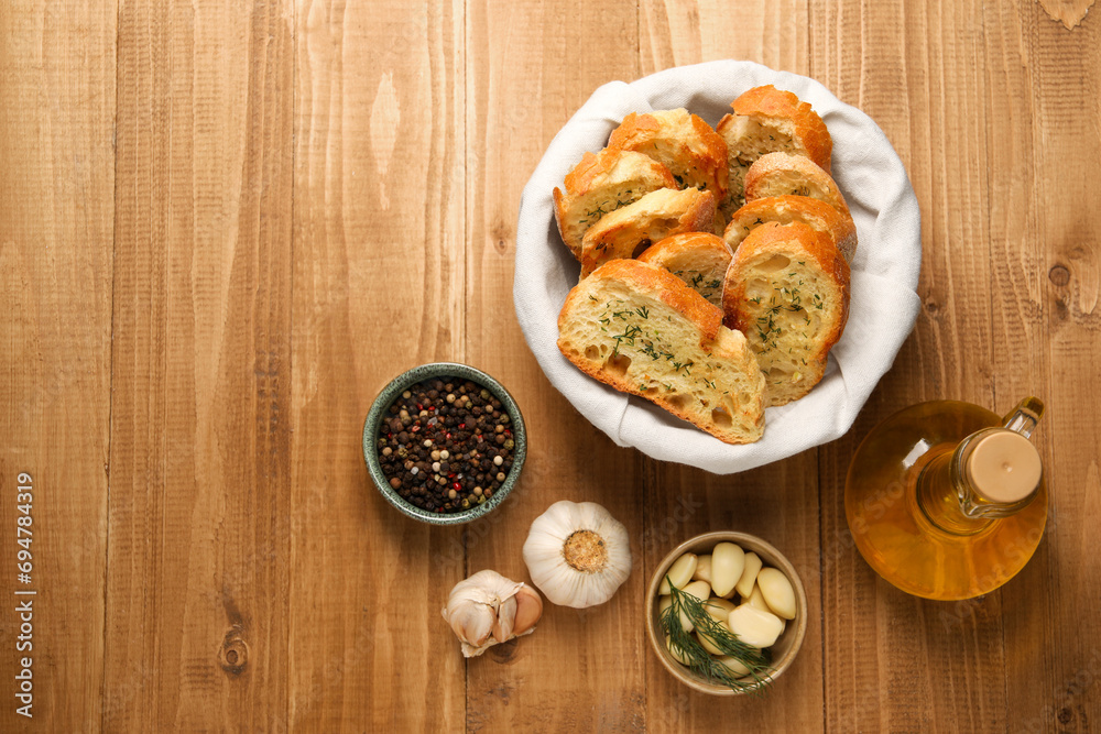 Tasty baguette with garlic, oil and other spices on wooden table, flat lay. Space for text Tasty baguette with garlic, oil and other spices on wooden table, flat lay. Space for text