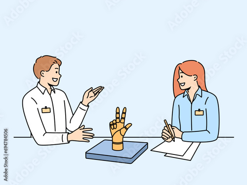 Meetings of office employees discussing robotization of production, sitting at table with robot arm and papers. Business man and woman talking agreeing on method for robotizing production process
