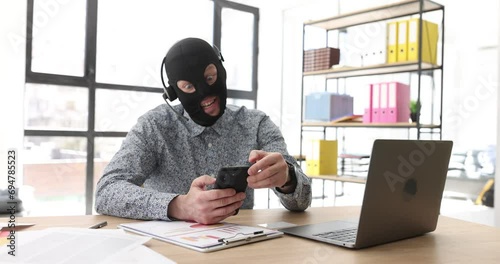 In the office, a scammer in a mask is talking on the phone, a close-up. Fraud circuit by phone, front view photo