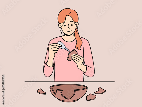 Woman seals broken clay plate to hide carelessness or demonstrate conscious consumption. Girl archaeologist with smile uses glue restoring clay dishes found at excavations for display in museum.