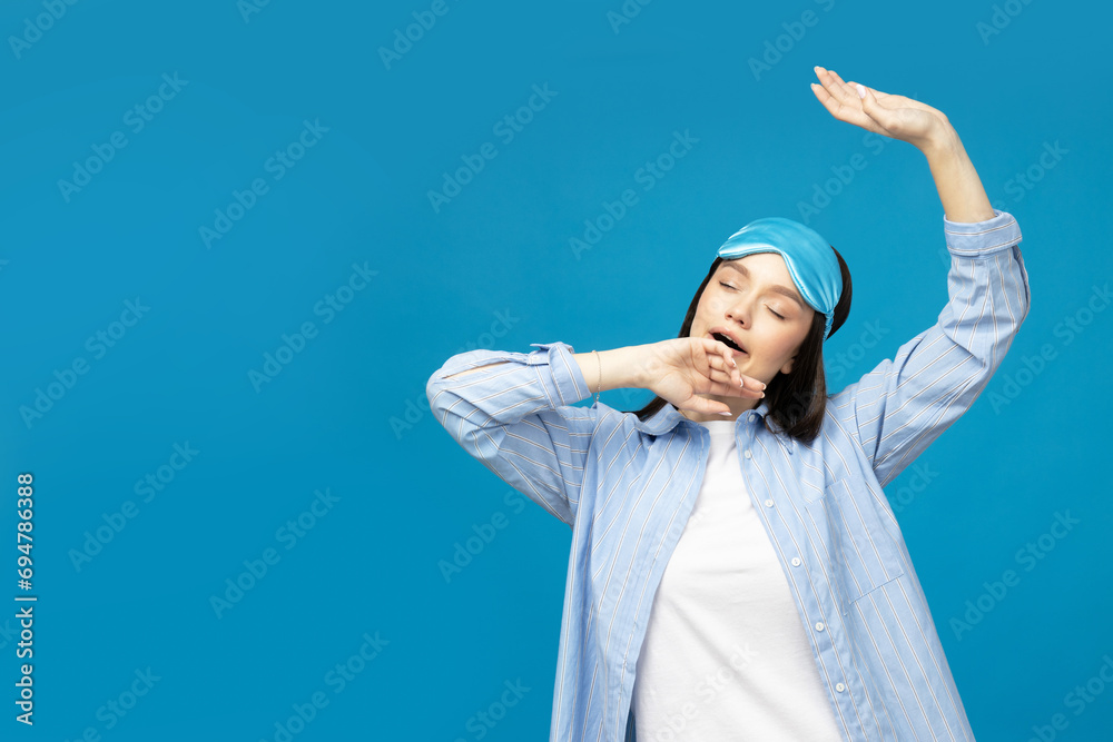 Naklejka premium Young woman in a sleeping mask on a blue background