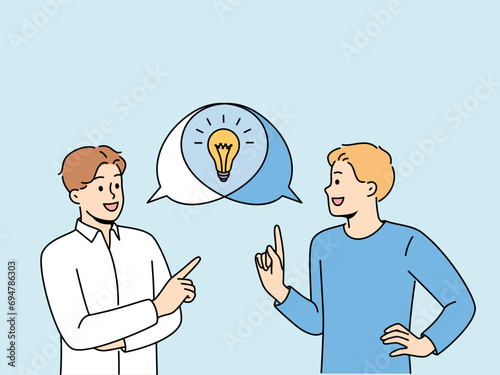 Man is doing joint brainstorming session, discussing ideas for making money, standing near speech bubbles with light bulb. Teamwork of student guys using brainstorming to find consensus