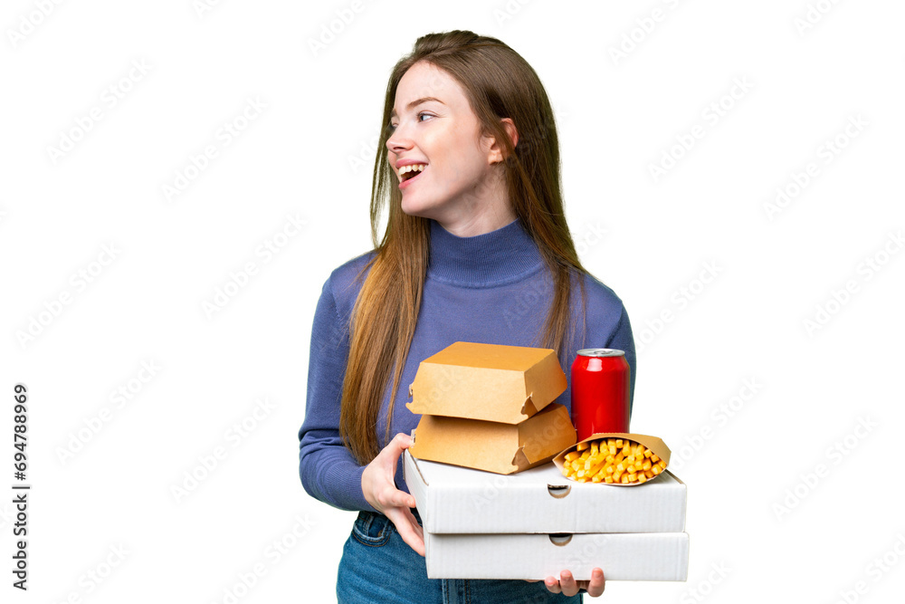 Young pretty woman holding pizzas and burgers over isolated chroma key background looking side Young pretty woman holding pizzas and burgers over isolated chroma key background looking side