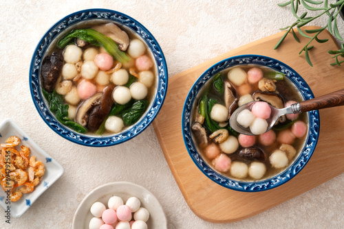 Eating homemade red and white small tangyuan with savory soup and vegetable. photo