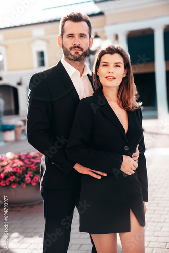  Beautiful fashion woman and her handsome elegant boyfriend in black suit. Sexy brunette model in jacket. Fashionable confident couple posing in street. Brutal man and female outdoors