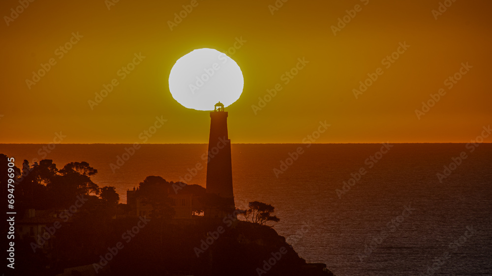 Fototapeta premium Coucher de soleil en bord de mer sur le phare de la presqu'île du Cap Ferrat depuis le Cap de Nice