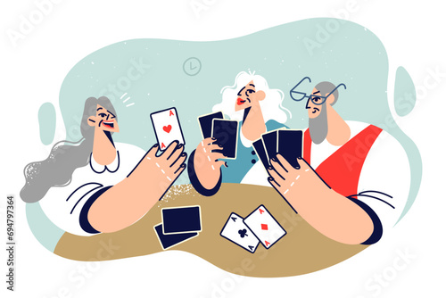 Cheerful elderly people play cards enjoying gambling entertainment in company friends from hospice