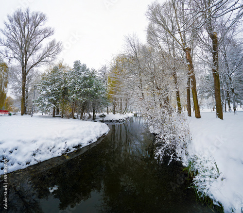 Dark waters of Seret river. Trees covered by frsh snow in Topilche park, Ternopil town, Ukraine, Europe. Stunning winter scene of city park. Beauty of nature concept background. photo