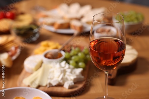Glass of rose wine and appetizers served on wooden table, selective focus. Space for text