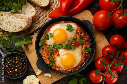 Flat lay composition with delicious shakshuka in frying pan on wooden table photo