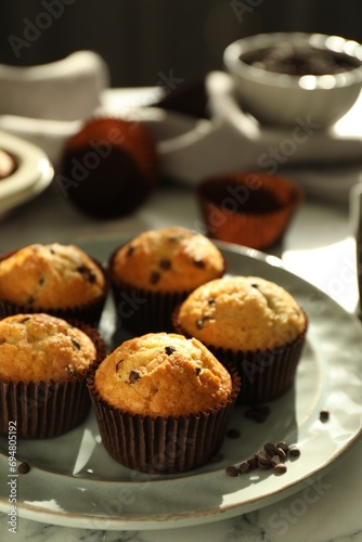 Delicious sweet muffins with chocolate chips on white marble table