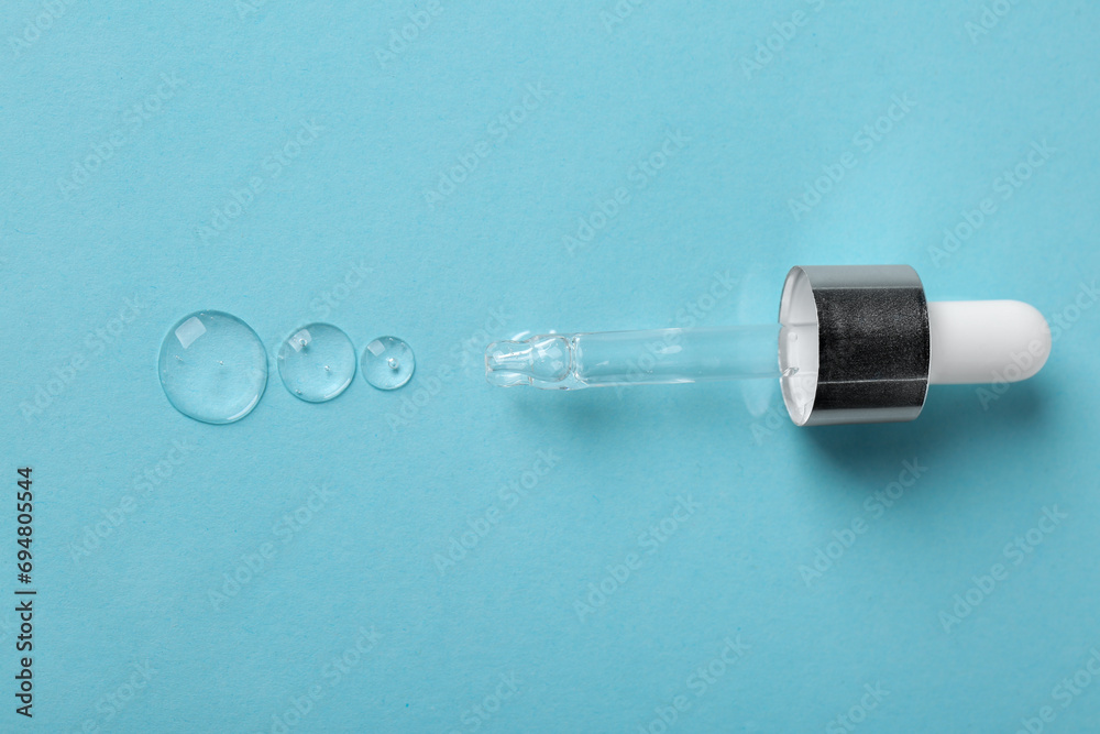 Clear cosmetic serum and pipette on light blue background, top view Clear cosmetic serum and pipette on light blue background, top view