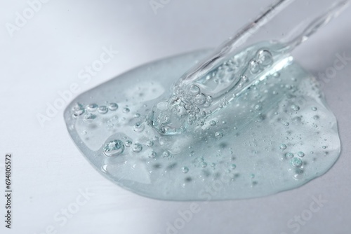 Pipette with cosmetic serum on white background, closeup