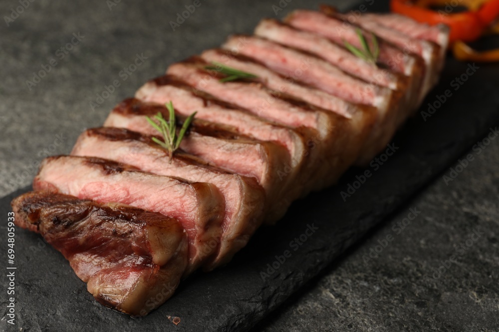 Delicious grilled beef steak with rosemary on dark gray table, closeup