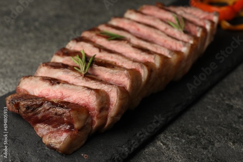 Delicious grilled beef steak with rosemary on dark gray table, closeup