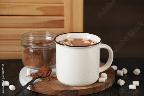 Cup of aromatic hot chocolate with marshmallows and cocoa powder served on table