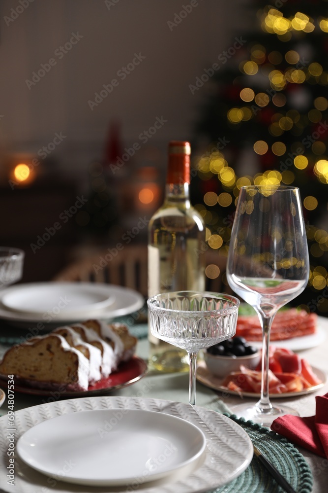 Christmas table setting with bottle of wine, appetizers and dishware indoors