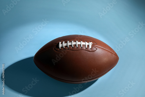 American football ball on light blue background