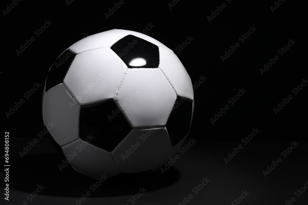 One soccer ball on black background, space for text. Sports equipment