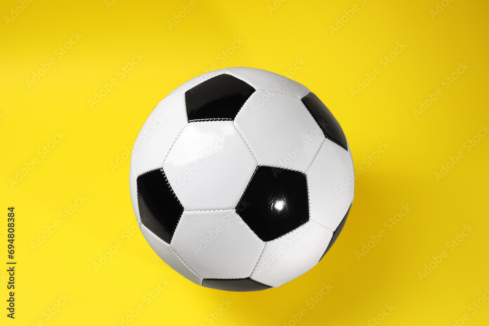 One soccer ball on yellow background, top view. Sports equipment One soccer ball on yellow background, top view. Sports equipment