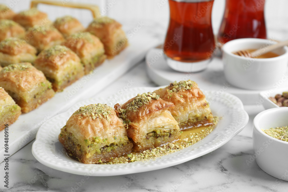 Delicious fresh baklava with chopped nuts and honey on white marble table, closeup. Eastern sweets