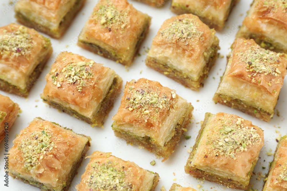 Delicious fresh baklava with chopped nuts on white table, closeup. Eastern sweets