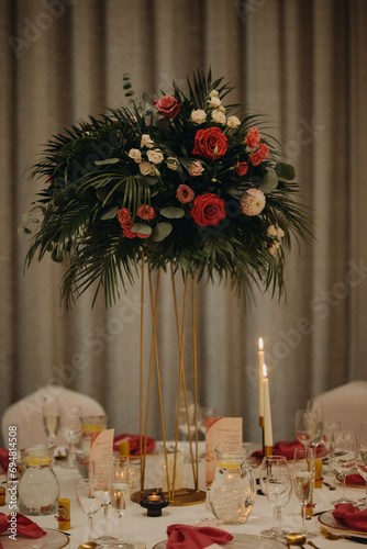 Elegant, romantic table setting for indoor wedding reception. Luxury wedding table decoration, special event table set up with fresh flowers arragements on high stands. photo