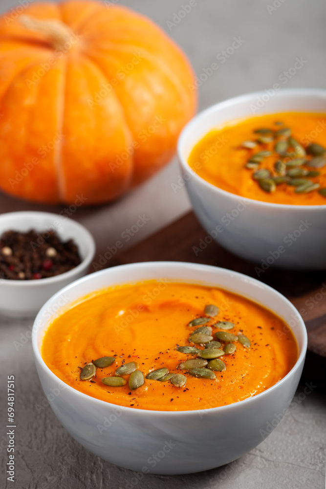 Pumpkin soup with seeds, spices, pepper on a gray background close up. The concept of healthy vegetable soups. Concept vegetarian food. Healthy seasonal autumn cuisine Pumpkin soup with seeds, spices, pepper on a gray background close up. The concept of healthy vegetable soups. Concept vegetarian food. Healthy seasonal autumn cuisine