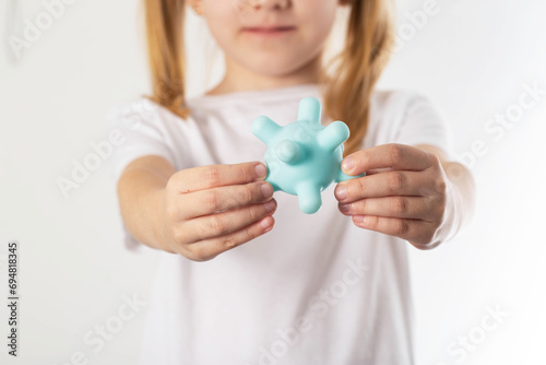 A blonde girl holds a model of a virus in her hands. Concept of infectious diseases in children, chickenpox and viral mumps, close-up photo
