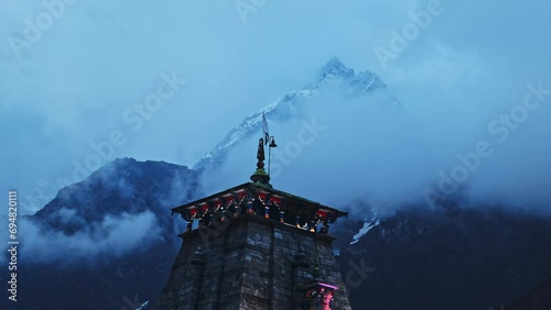 A beautiful shot of the cloudy and snowy Himalayan mountains behind the Kedarnath temple in Uttarakhand, India.