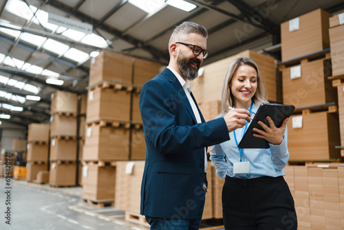Female warehouse manager talking with logistics employee in warehouse, planning transport of products, goods, talking shipping process. photo