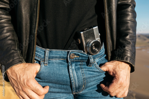 Vintage camera tucked in man's jeans with leather jacket photo